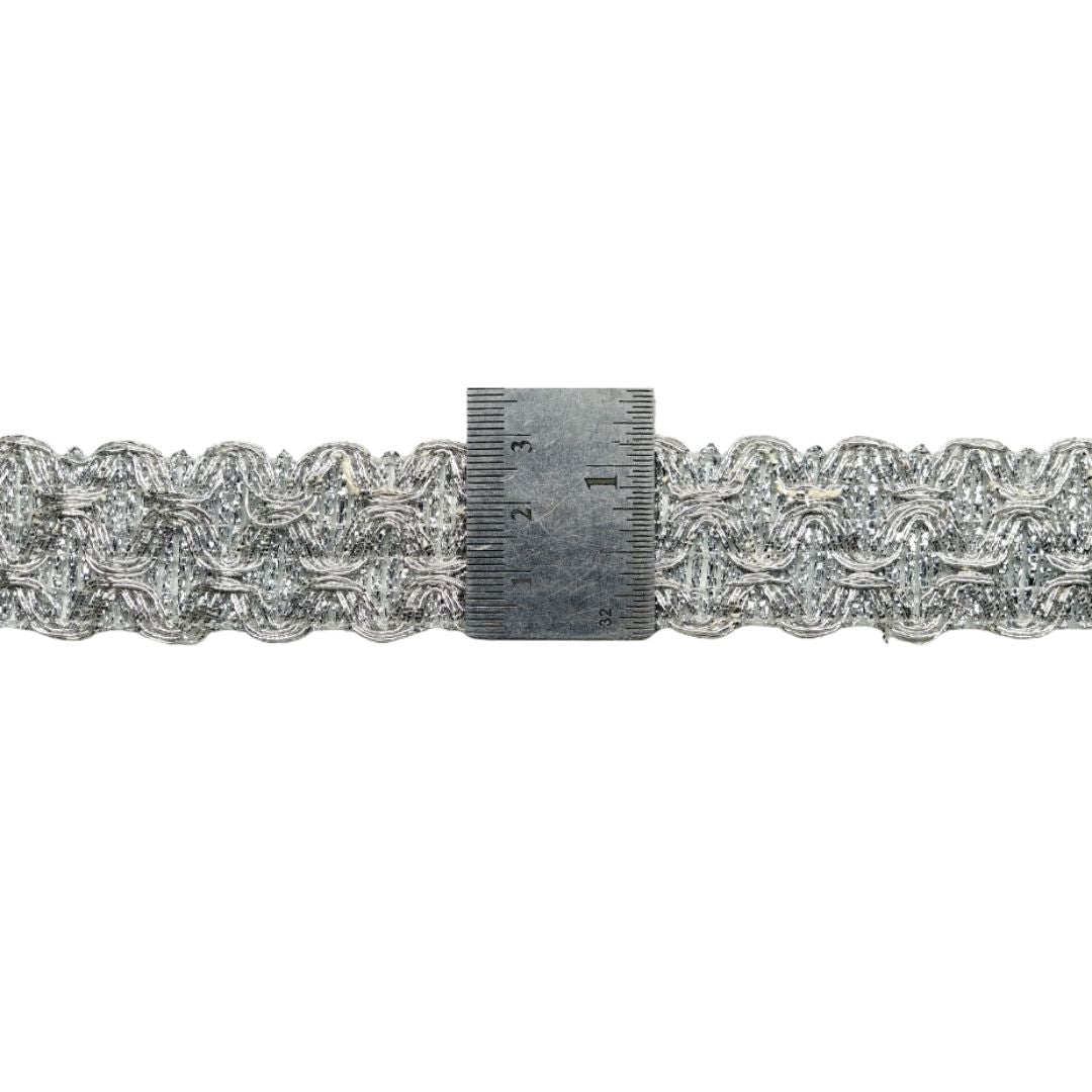 Decorative metallic lace trim with a ruler for scale on a white background